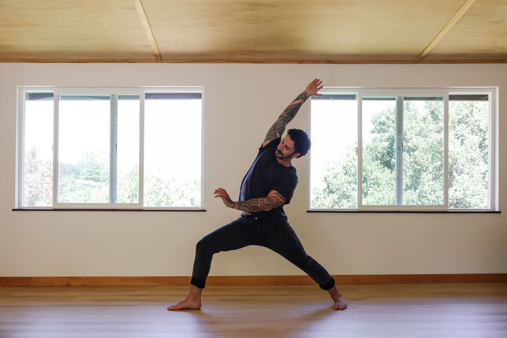 Peter Walters in reverse warrior in a pale wood yoga studio