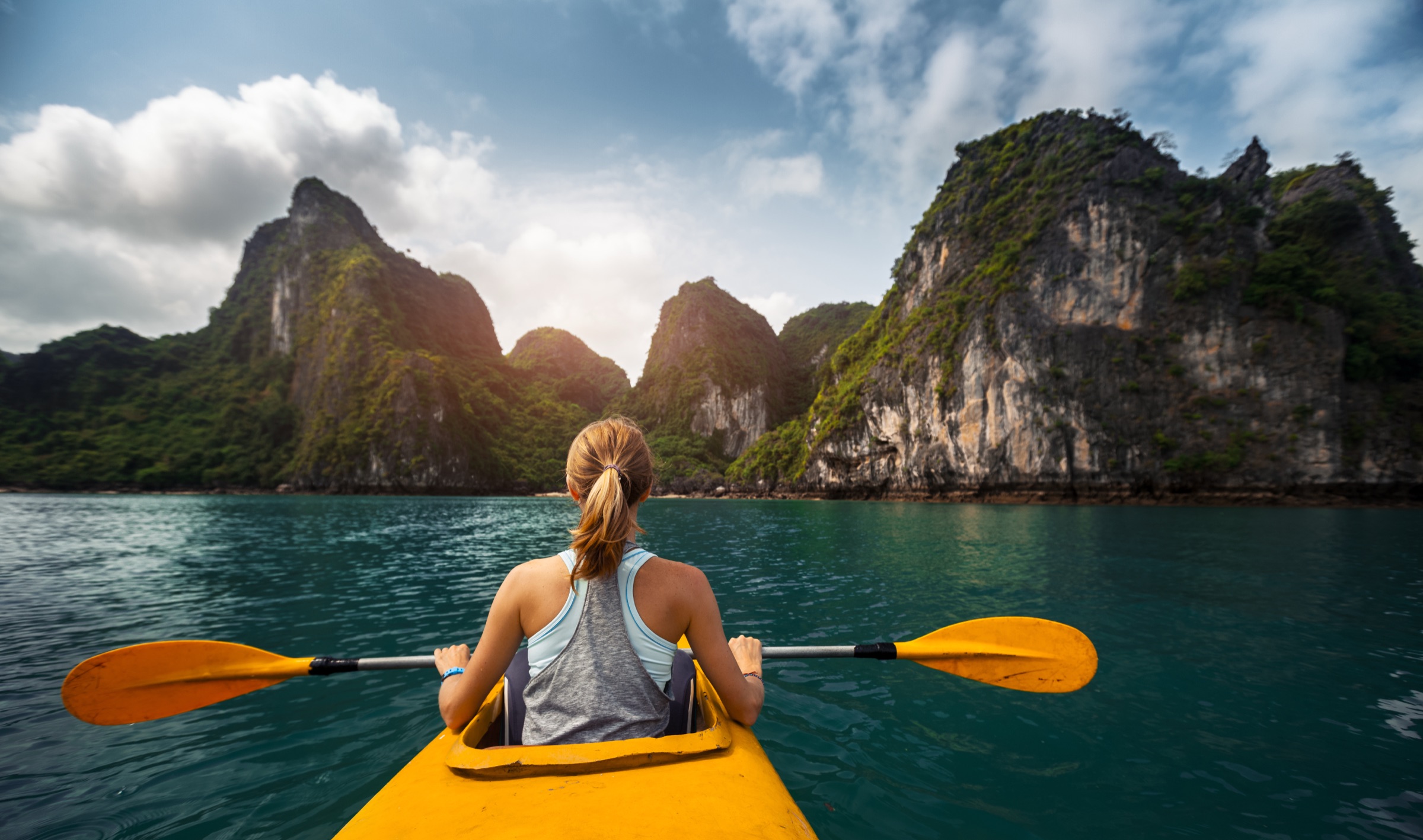 A kayaker paddling through the limestone karsts of Bai Tu Long Bay